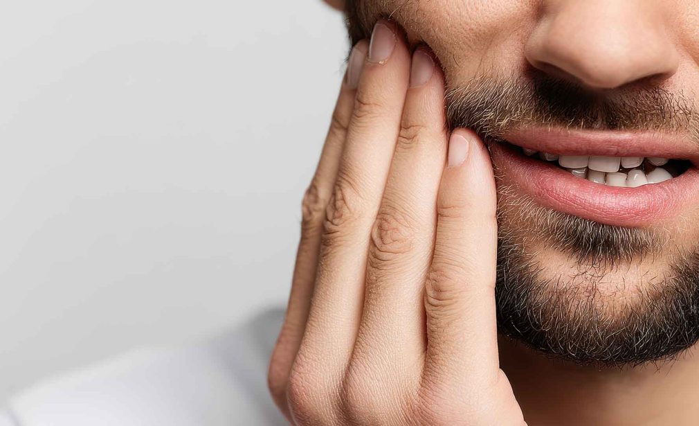 Patient holding his jaw because of tooth pain and seeking urgent dental care